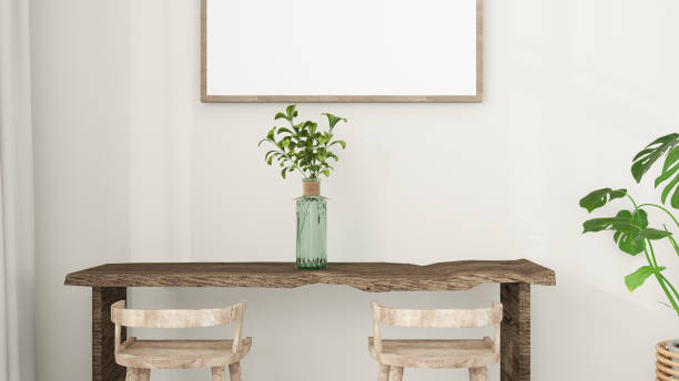 istock Close up of a minimalist interior scene featuring a rustic wooden table with two stools, a potted plant, and a blank picture frame on a light-colored wall. Home decor mockup. 2193055719