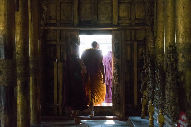 Two young buddhist monks are sitting and smiling at Sandamuni Paya pagoda in mandalay, myanmar
