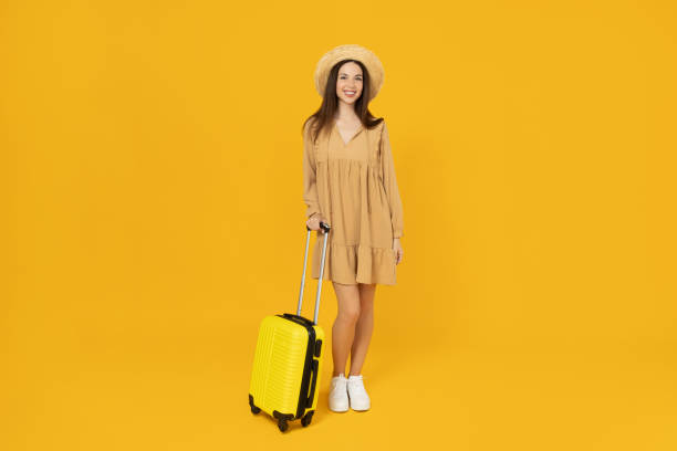 istock Young girl with a suitcase on a yellow background. 2193065980