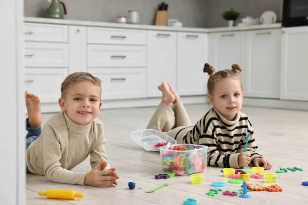 istock Cute little children playing together on warm floor in kitchen. Heating system 2193066686