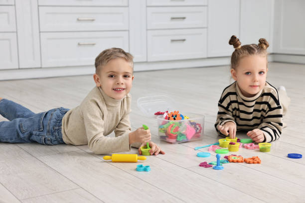 istock Cute little children playing together on warm floor in kitchen. Heating system 2193066727
