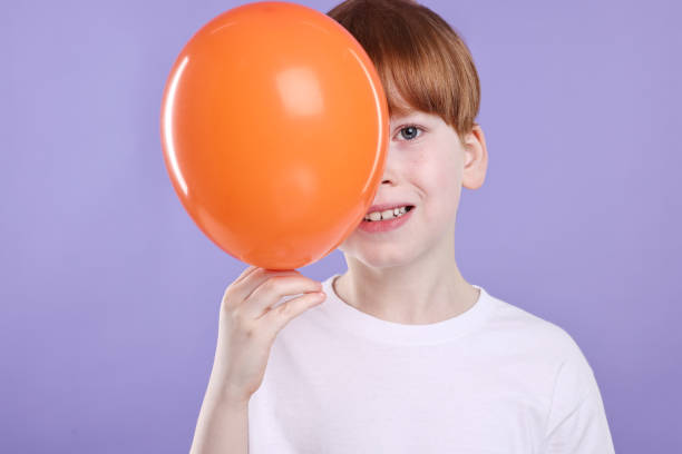 Boy with orange balloon on violet background