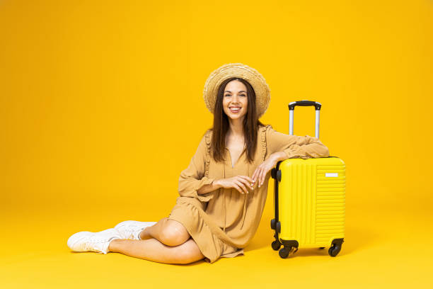 istock Young woman in a beach hat and a suitcase on a yellow background 2193067164