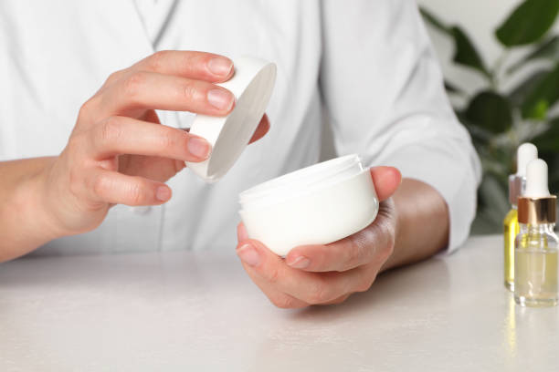 istock Dermatologist holding jar of cream at white table, closeup. Developing cosmetic product 2193067823