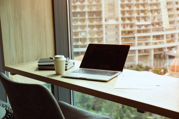 istock Office table by the window with coffee, laptop and notebooks 2193070610
