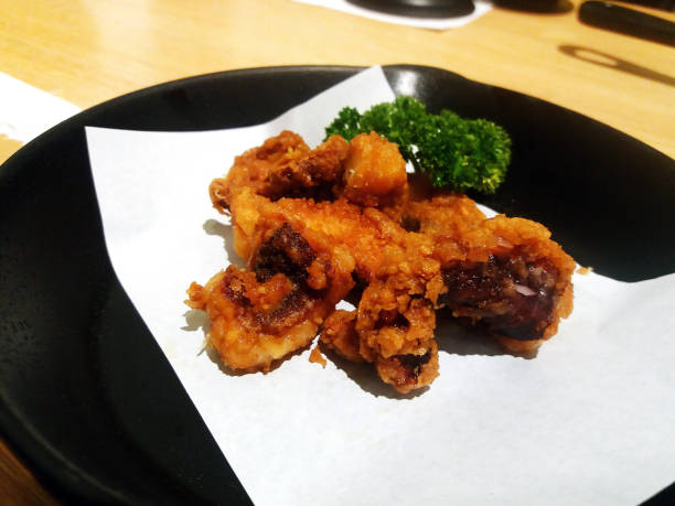 istock Deep fried crispy squid tentacles on black dish or plate at Japanese restaurant. Seafood food on table with copy space. 2193071948