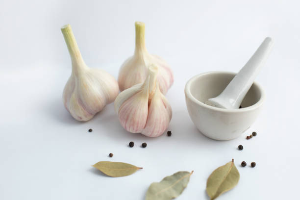 garlic and mortar with spices on a white background. selective focus