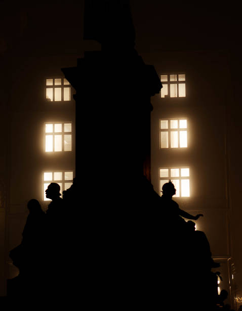 Dark silhouette of a monument with illuminated windows of a building in the background at night in krakow, poland