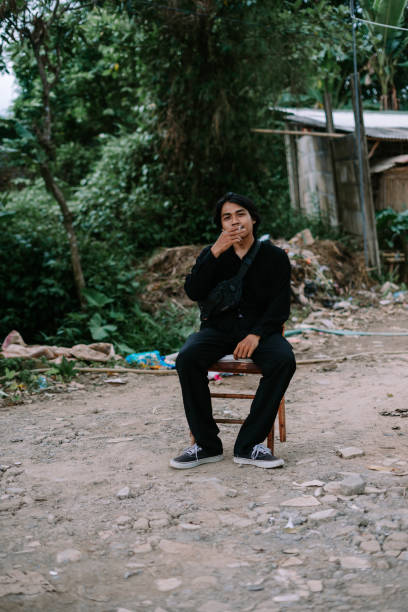 istock A Southeast Asian man sitting alone on a chair, smoking 2193073596