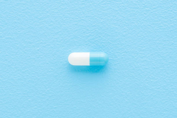 istock White blue pill on light blue table background. Closeup. Pastel color. Receiving vitamins or medicaments. Top down view. 2193078003