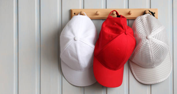 istock Different baseball caps hanging on wooden wall rack displaying variety and style 2193078356