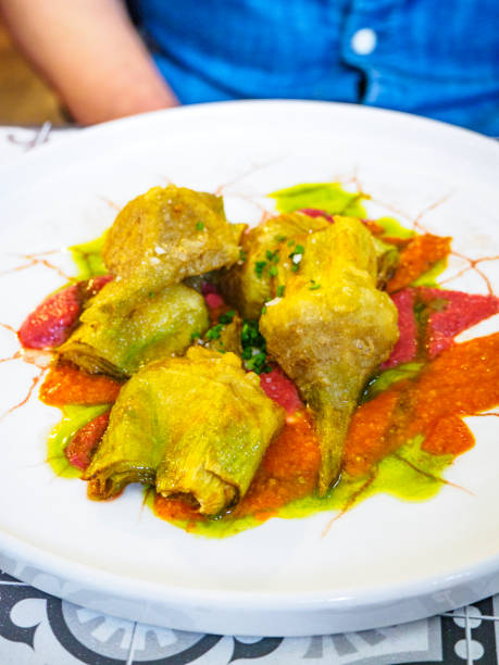 A plated dish of fried artichokes garnished with vibrant sauces in red and green, creating an artistic culinary presentation on a white plate.