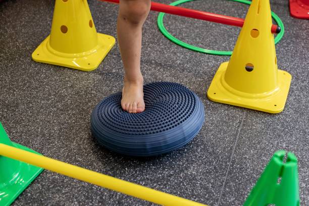 Child balancing on a sensory cushion in a colorful obstacle course indoors, focusing on coordination and motor skills.