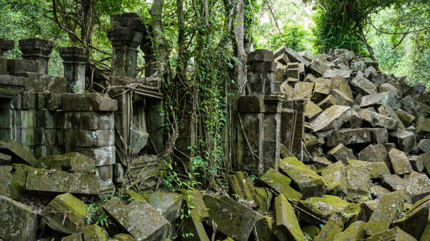 Abandoned Beng Mealea Temple Giant tropical rainforest trees growing over the Beng Mealea Temple Ruins and Stones. A ‚more unknown‘ temple from the Angkor Wat Time Period in Northern Cambodia. Beng Mealea was originally built as a Hindu temple, but some newer carvings depict Buddhist motifs. The history of the temple is unknown and it can be dated only by its architectural style, identical to Angkor Wat to the 12th century. 102 MegaPixel Hasselblad X2D Photo 16:9 Crop. Beng Mealea, Northern Cambodia, Siem Reap, Cambodia, South East Asia.
