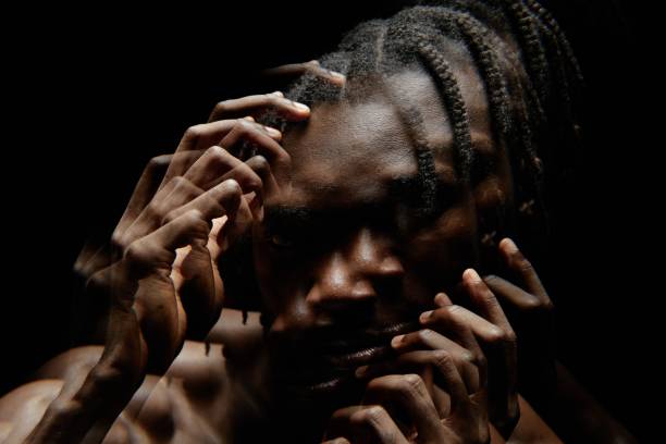 Distorted Portrait of Black Man Posing with Hands on Face in Contrast Light in Studio