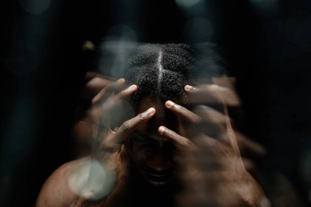 istock Black Man Covering Face with Hands Suffering from Headache in Contrast Light 2193086364