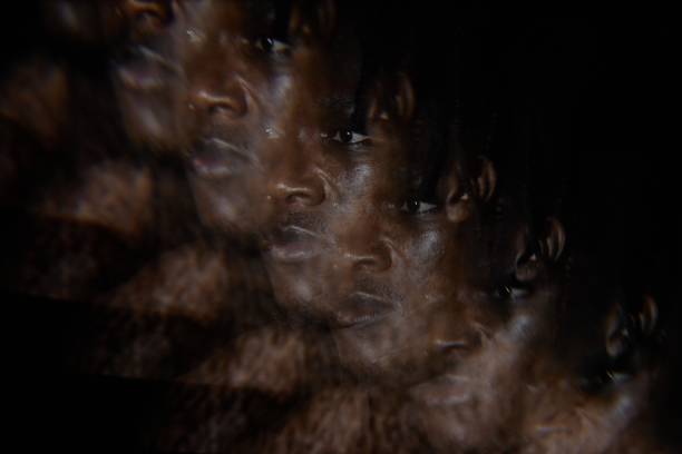 Abstract image with multiple exposure effect of African American man looking away wit sorrowful expression on face in low key light, copy space