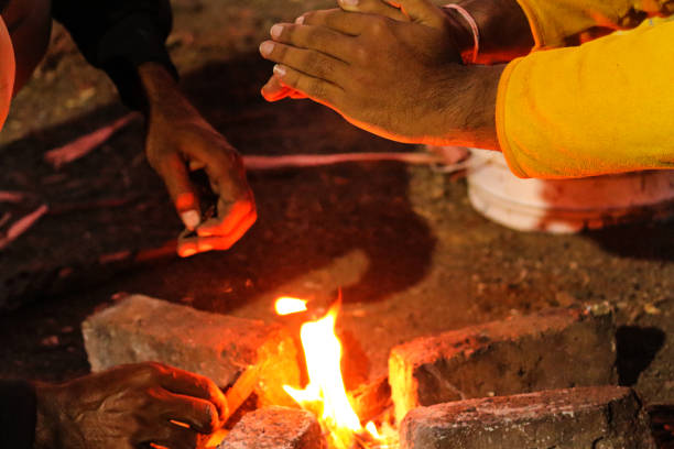 A woman in casual outdoor attire enjoys a warm campfire at night near a tent in a wilderness setting. Perfect for concepts of camping, adventure, outdoor activities, and relaxation.