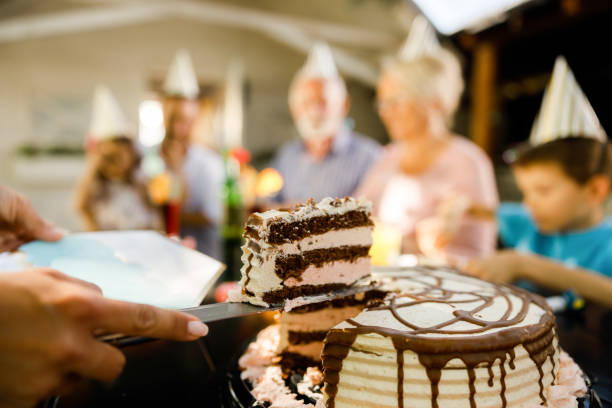 Close up of unrecognizable woman serving Birthday cake to her family.