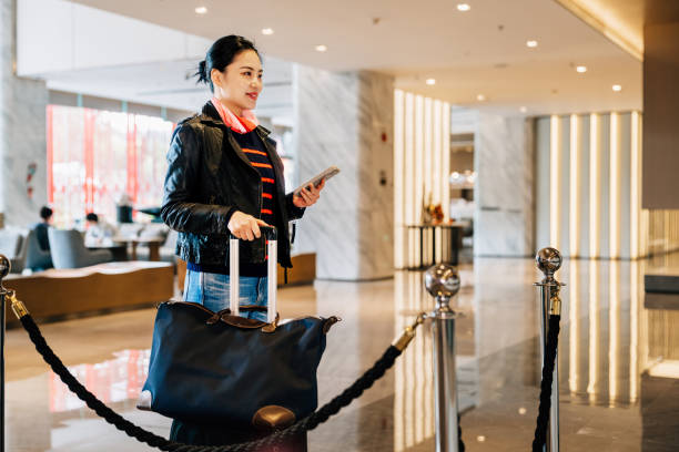 istock Asian businesswoman using mobile phone while waiting for checking-in at hotel reception desk. 2193089089