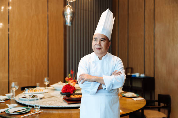 istock Portrait of Asian senior chef standing and smiling before restaurant table. 2193090461