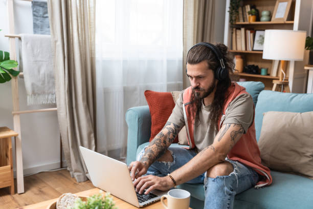 istock Handsome man listening to the music while working on a computer. Freelance IT security computer programer, global business professional occupation worker, work in home office on laptop. 2193090974