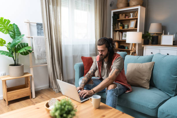 istock Handsome man listening to the music while working on a computer. Freelance IT security computer programer, global business professional occupation worker, work in home office on laptop. 2193090979
