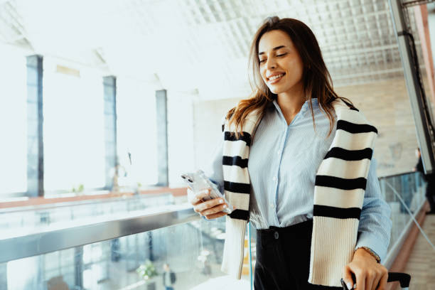 istock Smiling young woman using smartphone in modern bright office building while wearing casual stylish outfit and glasses 2193092749