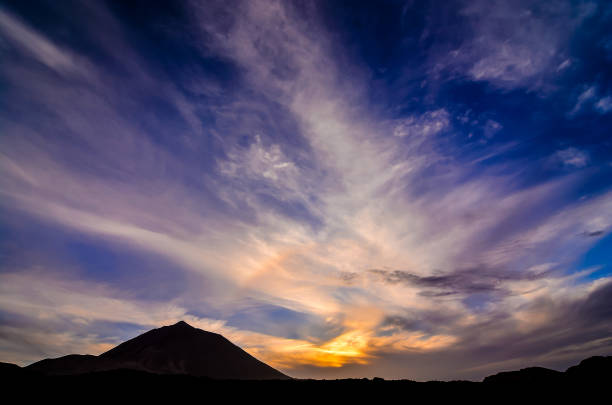 istock A mountain is silhouetted against a blue sky with clouds 2193094248