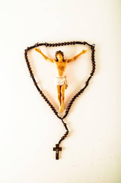 A small statue of Jesus Christ is suspended from a cross. The cross is made of wood and has a silver cross on it. The statue is positioned in the middle of the cross