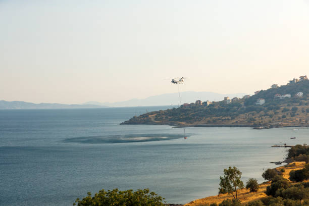An aerial firefighting operation in action, with a firefighting helicopter carrying water to combat a raging wildfire