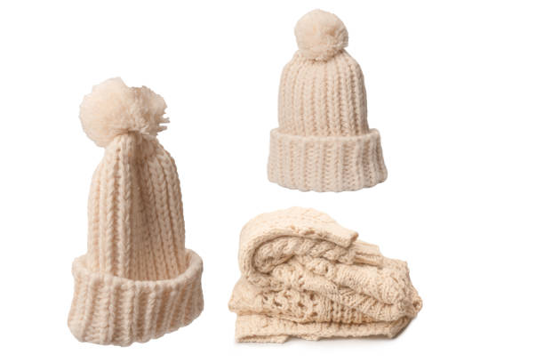 Beige warm beanie hat with pom pom isolated on a white background.