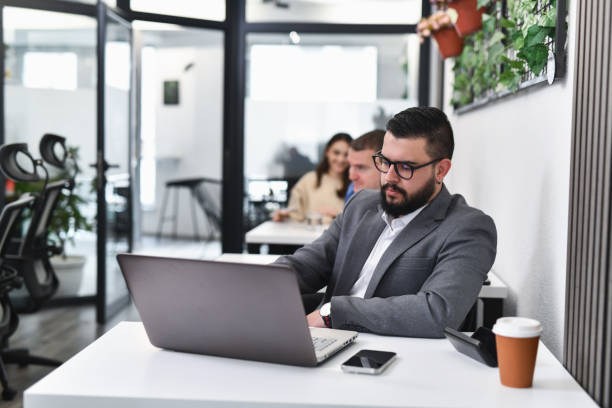 istock Male Entrepreneur Working From Co-working Space Typing on His Laptop Wearing Gray Suit 2193096232