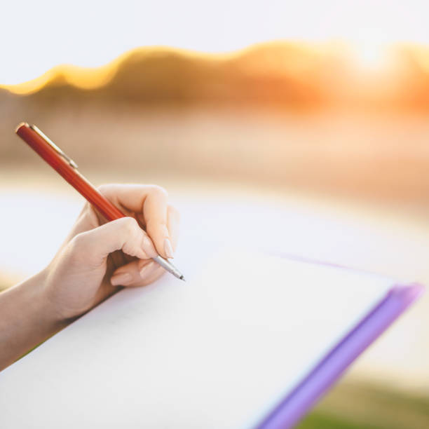 istock Woman Writing on Notebook Outdoors During Golden Hour 2193096957