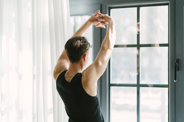 istock A man is stretching his arms in front of a window 2193098202