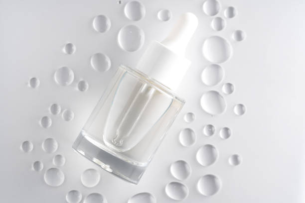 Moisturizing serum in glass bottle with dropper on white background. Top view, flat lay, mock up.