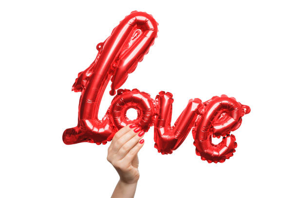 istock Holding a shiny red love balloon against a white background. A hand extends upward, presenting a vibrant, shiny red balloon shaped like the word love. 2193104877