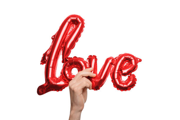 istock Hand holding shiny red balloon shaped like the word love, symbolizing romance and affection 2193104907