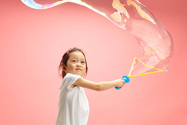 istock Funny Little Asian Girl Making Big Soap Bubbles on Pink Isolated 2193107316