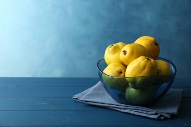 istock Tasty ripe quinces in bowl on blue wooden table, space for text 2193109369