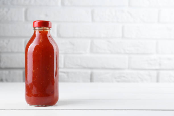 istock Spicy chili sauce in bottle on white wooden table, space for text 2193109455