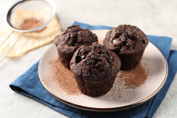 istock Delicious chocolate muffins and cacao powder on light grey table, closeup 2193110920