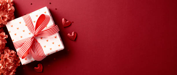 istock Valentine's day gift. Banner design with present box, flowers, and hearts on red background. 2193111884