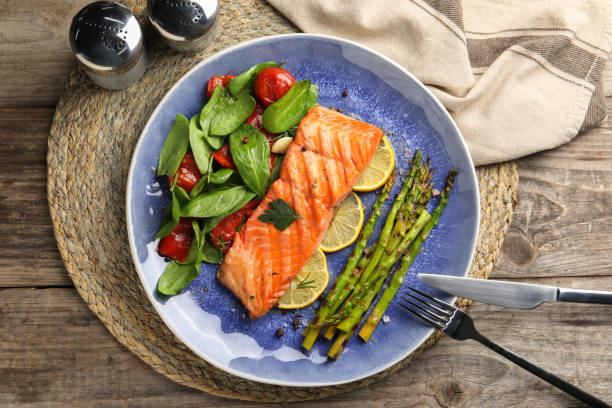 istock Tasty grilled salmon with tomatoes, asparagus, spinach and lemon served on table, flat lay 2193112580