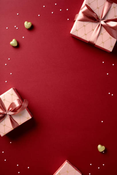Frame of Valentine's day gift boxes with heart shaped candies on red vertical background.