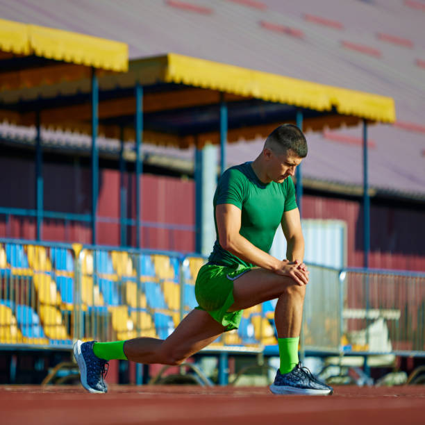 Young athletic man stretching legs before marathon on field outdoor. Training session on start line. Concept of sport, tournament, motivation, workout. Ad