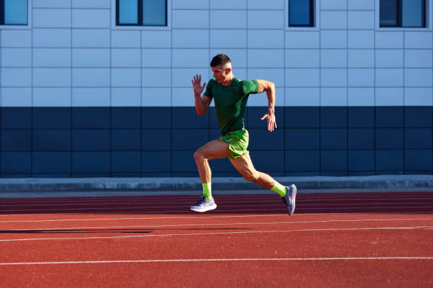 istock Young athlete man in uniform, sprinter running in motion on track to finish line. Speed and victory. Dynamic and energy. 2193117007