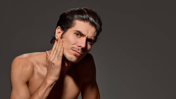 istock Man looking upward slightly, shows soft smile against dark background. His posture and sleek hairstyle suggest ease and confidence. 2193118058