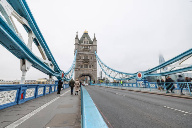 A Hispanic tourist enjoys a leisurely walk on London's iconic Tower Bridge. The scene captures the beauty and vibrant atmosphere of urban exploration, reflecting joy and relaxation during travel.