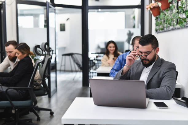 istock Focused Businessman Putting on Blue Light Blocking Glasses Preparing For Long Day in Front of Screen 2193122611